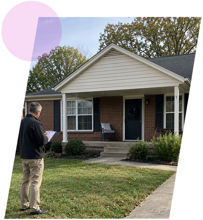 Home inspector taking notes on clipboard outside a brick single-family house in Jeffersontown, KY.