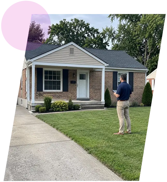 Property inspector standing on the front lawn taking notes in front of a brick house in Shively, KY.