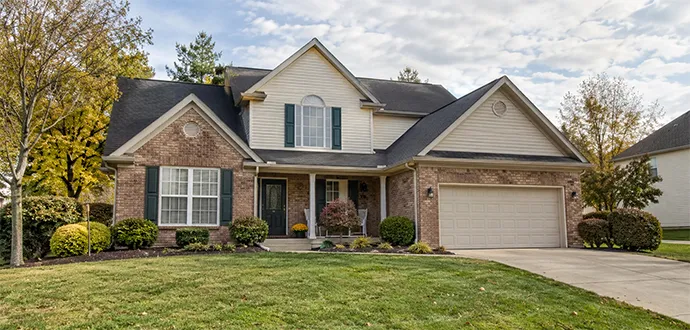 Suburban brick home with dark shutters, front porch, attached garage, and manicured green lawn in Middletown, KY.